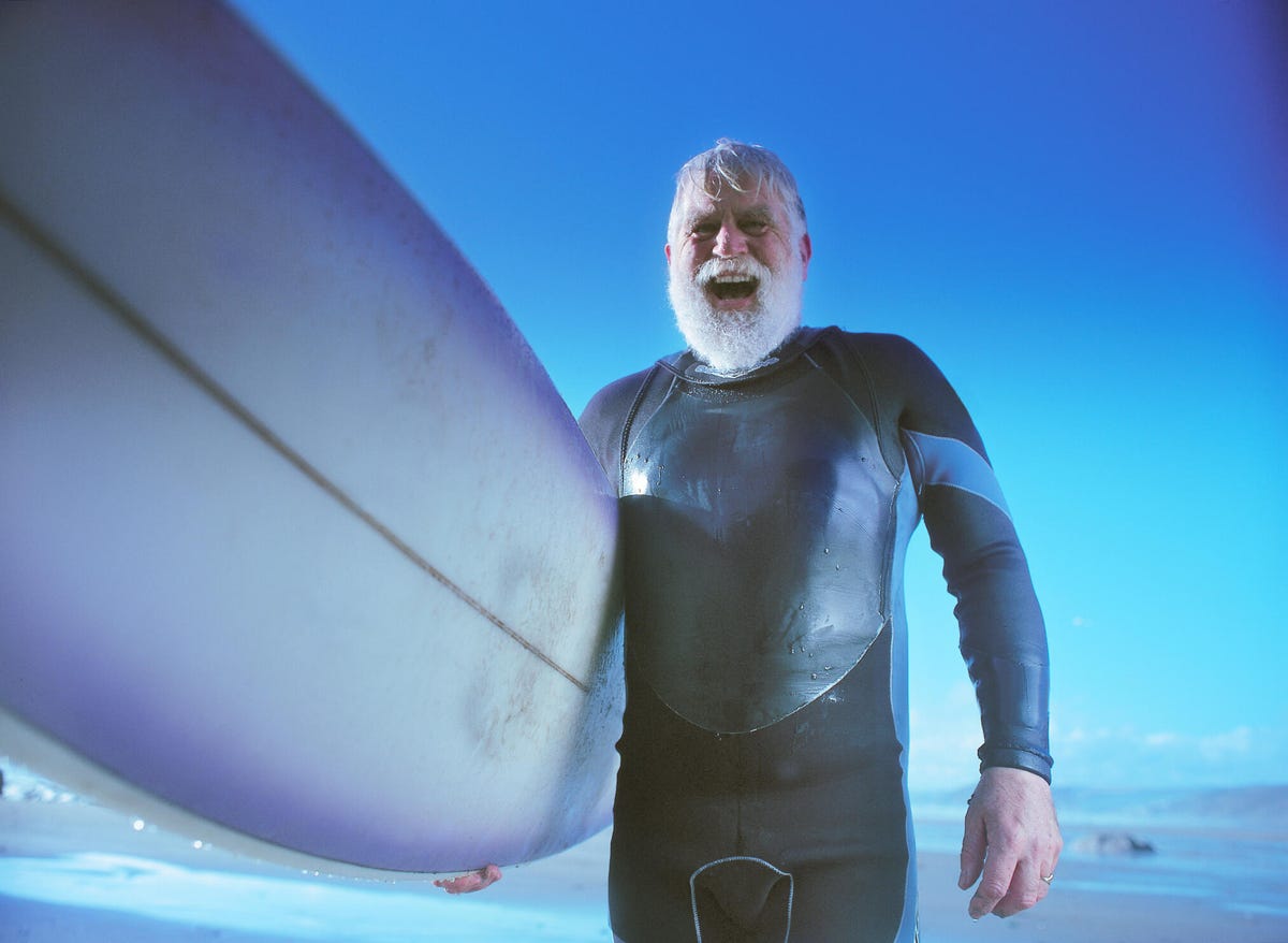 A bearded man holding a board in the water