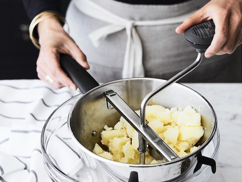 A person is using a mill to make mashed potatoes