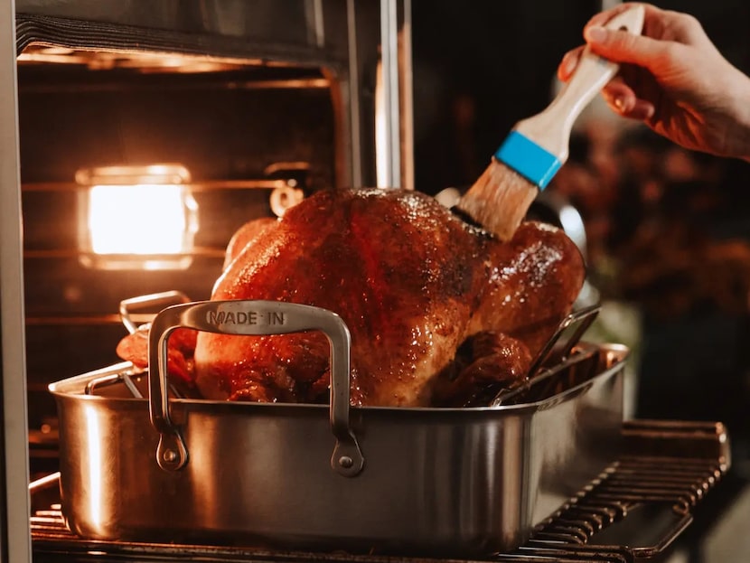 Turkey in the oven in a stainless steel roasting pan